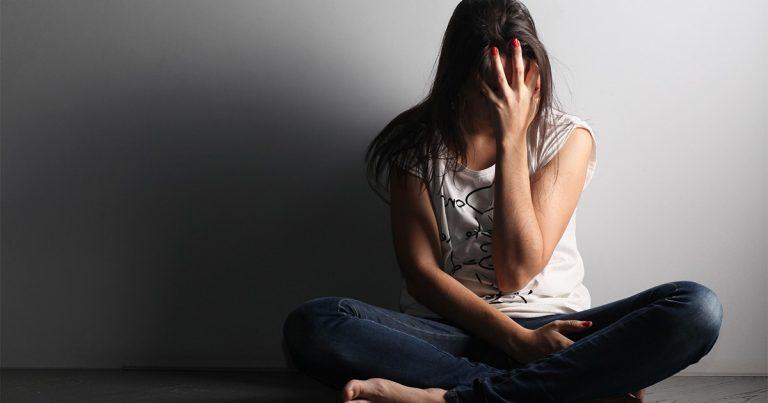 Medical Detox - Person with face in hand and white backdrop dealing with withdrawal.