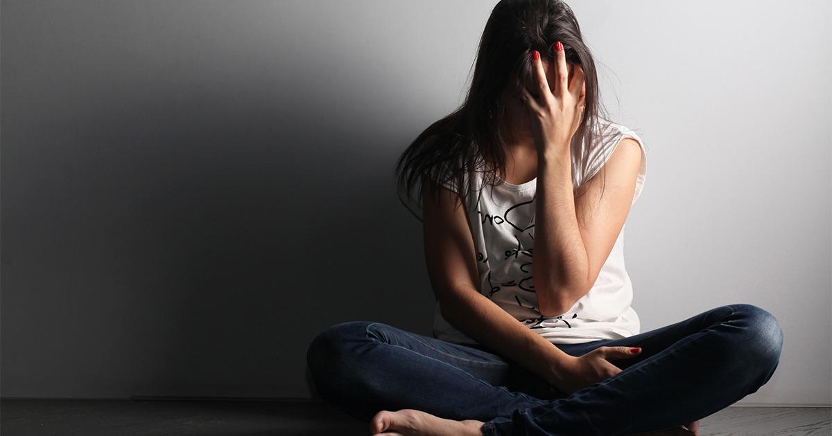 Medical Detox - Person with face in hand and white backdrop dealing with withdrawal.
