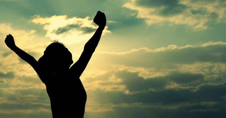 Resilience in Addiction Recovery - Person facing the sky with arms out and clouds in the background