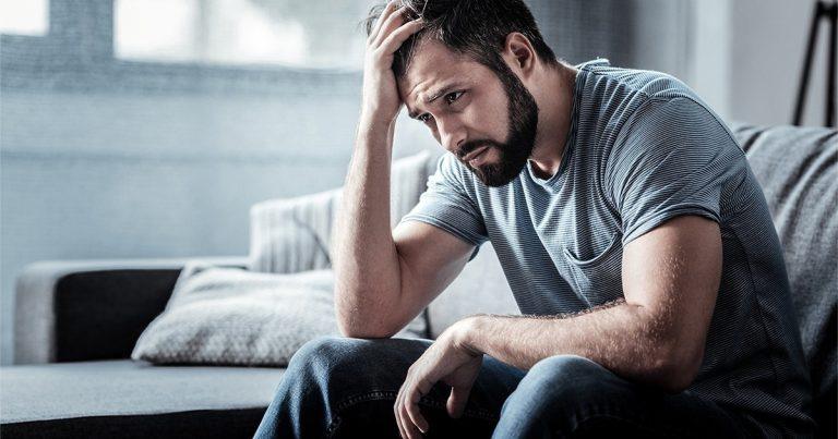 Understanding Addiction in Men - Stressed looking man siting on a couch
